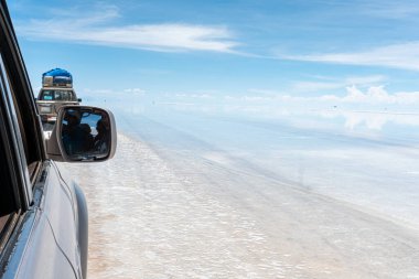 Bolivya 'daki Salar de Uyuni' de su ile kaplı araba ve bulutların yansımaları