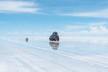 Bolivya 'daki Salar de Uyuni' de su ile kaplı araba ve bulutların yansımaları
