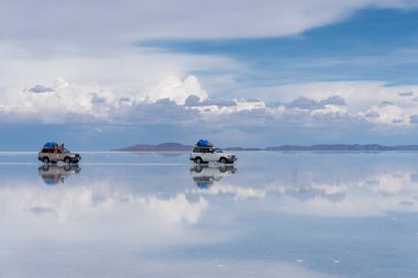 Bolivya 'daki Salar de Uyuni' de su ile kaplı araba ve bulutların yansımaları