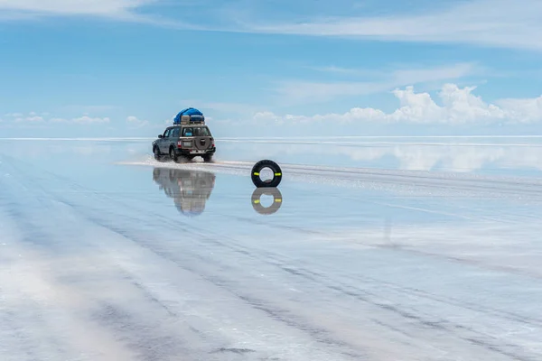 Bolivya 'daki Salar de Uyuni' de su ile kaplı araba ve bulutların yansımaları