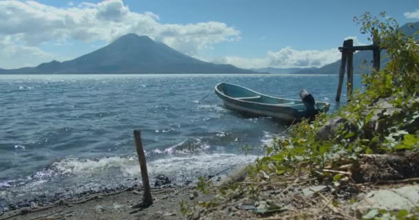 Un pequeño barco en un cuerpo de agua con el lago Atitlán en el fondo — Vídeo de stock