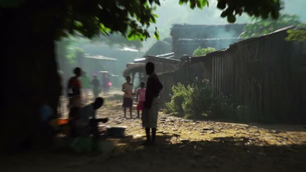 Africká vesnice. Lidé odpočívají ve stínu — Stock video