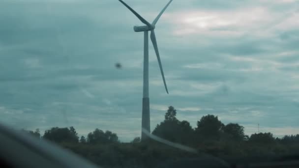 夏の曇りの日に木の間の車の窓から壊れた風車が — ストック動画