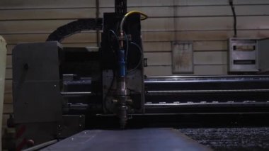 Elektrikli bir panelin arka planında, yetersiz aydınlatılmış bir odada, metalden otomatik lazer kesimi kıvılcımlar.