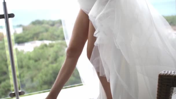 在阳光灿烂的夏日 年轻的新娘穿着运动鞋和婚纱在阳台上炫耀美丽的双腿 — 图库视频影像