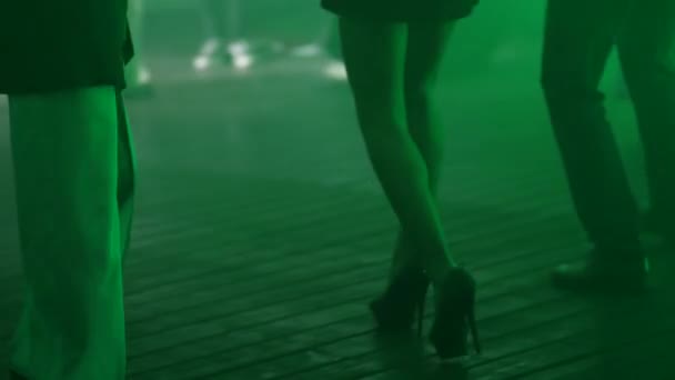 一个穿着短裙 穿着高跟鞋 光溜溜的小女孩的美丽腿 在人群中的夜总会里随着音乐翩翩起舞 — 图库视频影像