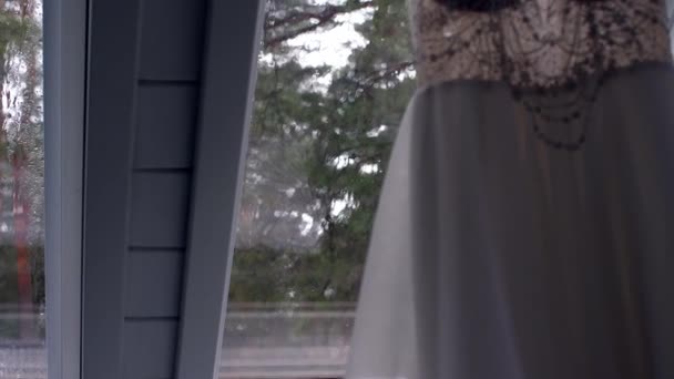 雨粒がノックする窓ガラスの背景に吊るされた美しい透かし彫りのウェディングドレス — ストック動画