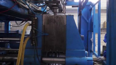 Ekstrüzyon ekipmanında plastik tankların patlatılması. Erimiş beyaz plastik bir tüp gibi baskı formuna sokulur ve hava üflenir ve şişenin şekli verilir.