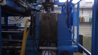 Ekstrüzyon ekipmanında plastik tankların patlatılması. Erimiş beyaz plastik bir tüp gibi baskı formuna sokulur ve hava üflenir ve şişenin şekli verilir.