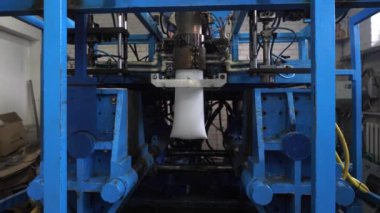 Ekstrüzyon ekipmanında plastik tankların patlatılması. Erimiş beyaz plastik bir tüp gibi baskı formuna sokulur ve hava üflenir ve şişenin şekli verilir.