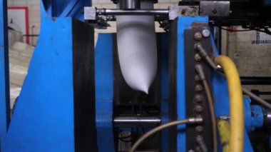 Ekstrüzyon ekipmanında plastik tankların patlatılması. Erimiş beyaz plastik bir tüp gibi baskı formuna sokulur ve hava üflenir ve şişenin şekli verilir.