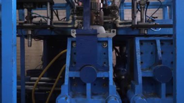 Ekstrüzyon ekipmanında plastik tankların patlatılması. Erimiş beyaz plastik bir tüp gibi baskı formuna sokulur ve hava üflenir ve şişenin şekli verilir.