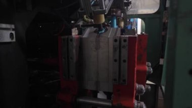 Ekstrüzyon ekipmanında plastik tankların patlatılması. Erimiş beyaz plastik bir tüp gibi baskı formuna sokulur ve hava üflenir ve şişenin şekli verilir.