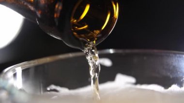 Hafif bira ya da gazoz şişeden bardağa dökülür, kabarcıklar aşağı akar, köpük yükselir - makroda yakın çekim