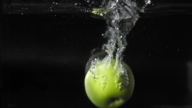 Yeşil elma suya düşer, izole edilmiş, yavaş çekim, suda kabarcıklar, 180fps sıçrar.
