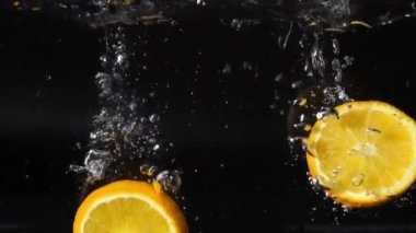 Bir dilim portakal suya köpüklerle, kabarcıklarla ve köpüklerle düşer.