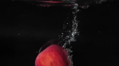 Kırmızı elmalar suya düşer, kabarcıklar ve kabarcıklar ile ve 180 fps yüzer.