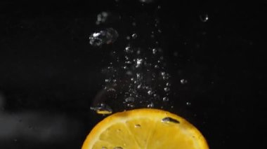 Bir dilim portakal suya köpüklerle, kabarcıklarla ve köpüklerle düşer.