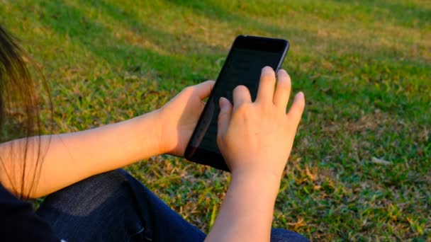 Kobieta przy użyciu telefonu komórkowego w parku — Wideo stockowe