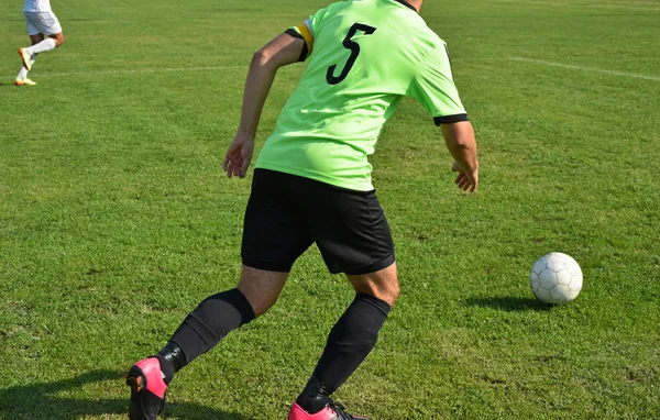 Voetbalspeler wordt uitgevoerd met een bal — Stockfoto