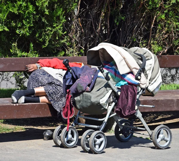 Mulher sem-teto dorme em um banco de parque — Fotografia de Stock