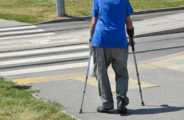 Old man walks with crutch