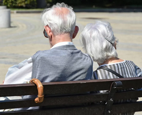 Casal velho senta-se em um banco — Fotografia de Stock