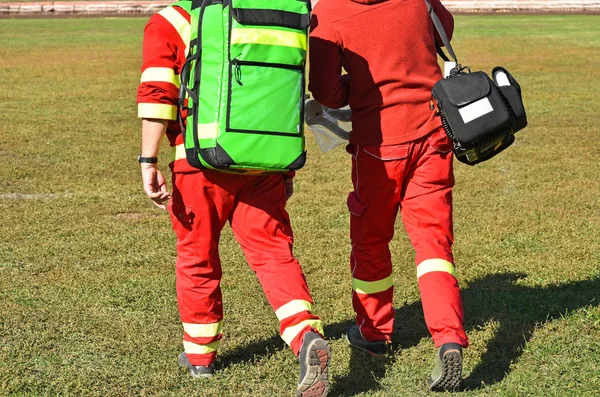 Ambulance staff with medical equipment on a sport track
