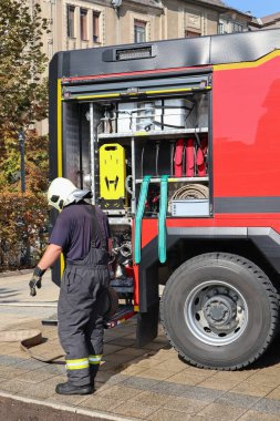 İtfaiyeci kamyonun yanında.