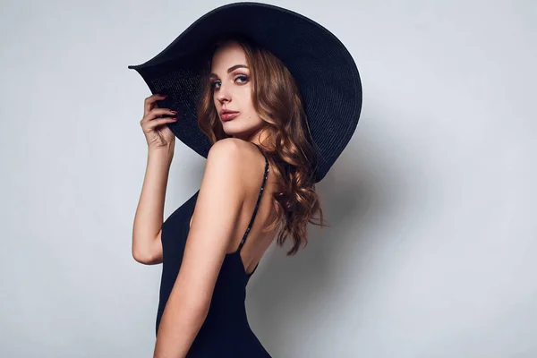 Κομψό όμορφη γυναίκα σε ένα μαύρο φόρεμα και καπέλο — Φωτογραφία Αρχείου