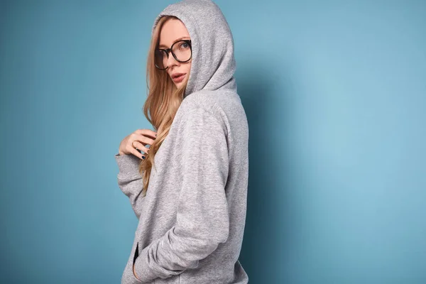 Roztomilý pozitivní blond žena v šedá s kapucí a brýle — Stock fotografie