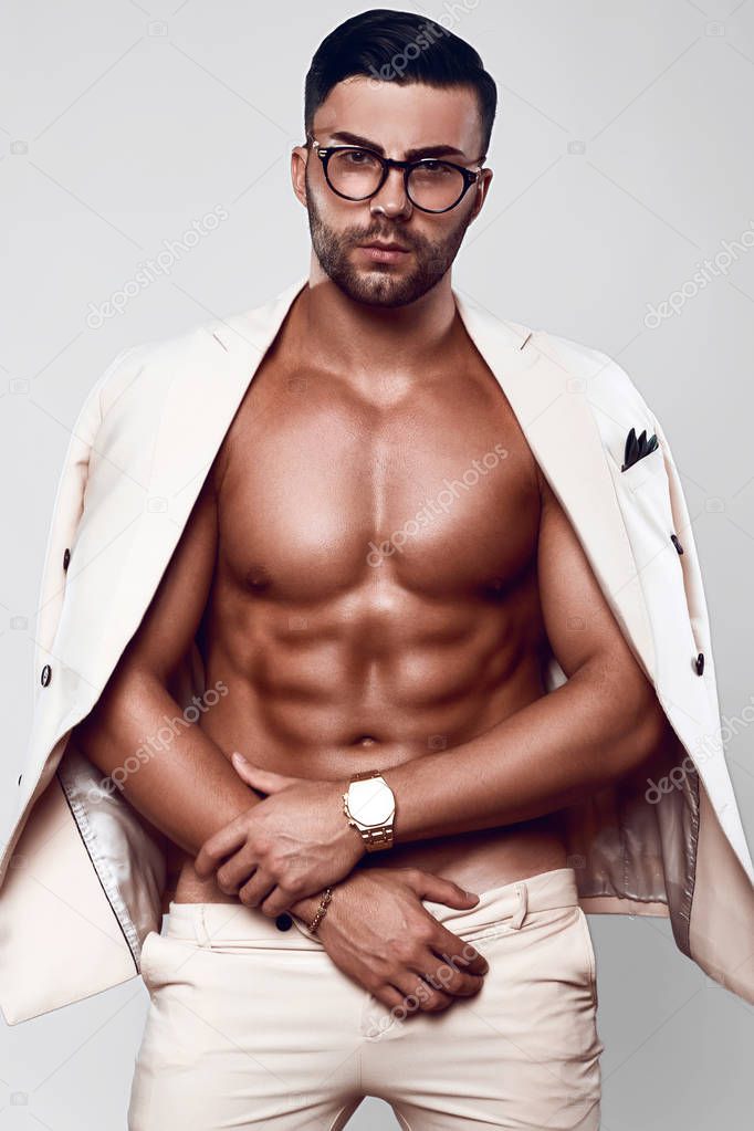 Elegant fit brutal man model in a light suit and glasses