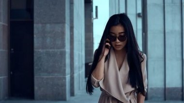 Sevimli ve güzel Asyalı kadın ceket sütunlar arasında yürüyüş