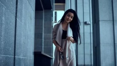 Sevimli ve güzel Asyalı kadın ceket sütunlar arasında yürüyüş