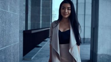 Sevimli ve güzel Asyalı kadın ceket sütunlar arasında yürüyüş