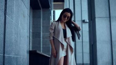 Sevimli ve güzel Asyalı kadın ceket sütunlar arasında yürüyüş