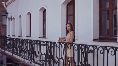 Balkonda duran ve kokteyl içme elbise sevimli ve muhteşem latin kadın