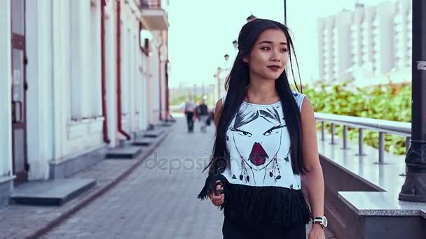 Preciosa mujer asiática en vestido de moda caminando a lo largo de brillante calle europea — Vídeos de Stock