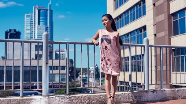 Mujer asiática linda y brillante en vestido de moda admirando la vista de la ciudad — Vídeos de Stock