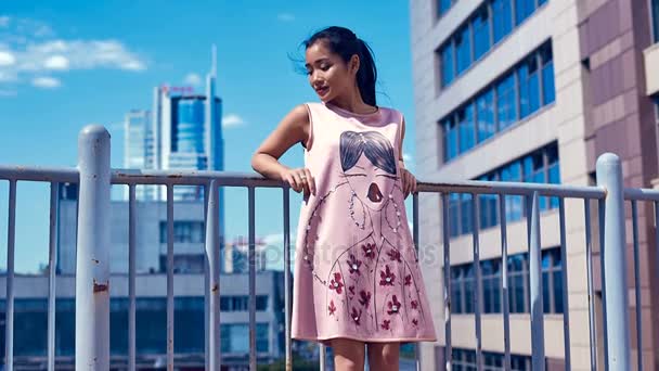 Mujer asiática linda y brillante en vestido de moda admirando la vista de la ciudad — Vídeos de Stock