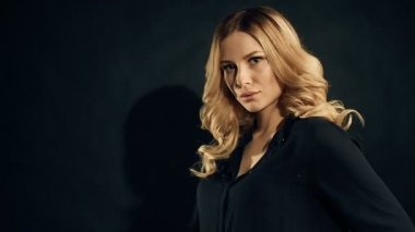 Studio siyah arka plan üzerine poz kıvırcık saçlı sarışın kadın