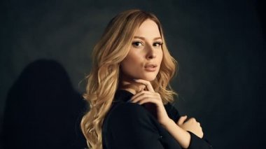 Studio siyah arka plan üzerine poz kıvırcık saçlı sarışın kadın