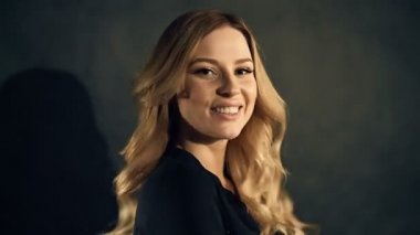 Studio siyah arka plan üzerine poz kıvırcık saçlı sarışın kadın