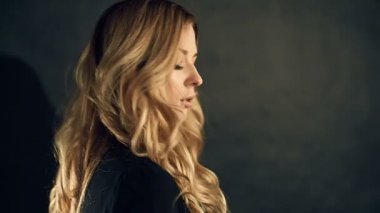 Studio siyah arka plan üzerine poz kıvırcık saçlı sarışın kadın