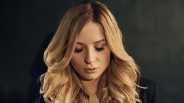 Studio siyah arka plan üzerine poz kıvırcık altın saçlı sarışın kadın