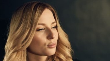 Studio siyah arka plan üzerine poz kıvırcık altın saçlı sarışın kadın