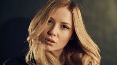 Studio siyah arka plan üzerine poz kıvırcık altın saçlı sarışın kadın