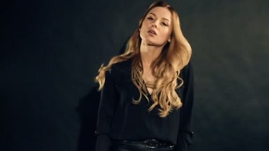Studio siyah arka plan üzerine poz kıvırcık saçlı sarışın kadın