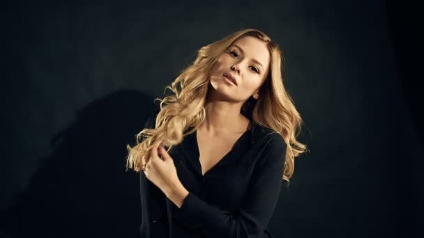 Mulher loira com cabelo encaracolado posando em fundo preto no estúdio — Vídeo de Stock