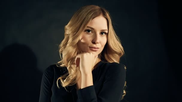 Blonde vrouw met krullend haar poseren op een zwarte achtergrond in de studio — Stockvideo